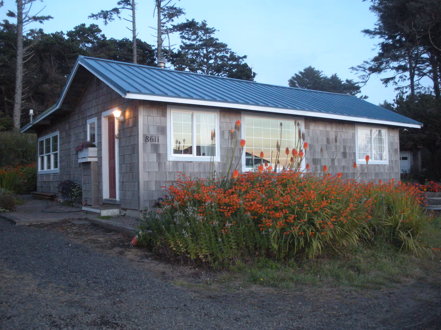 The Cottage exterior in the evening light, surrounded by blooming red-hot-poker flowers
